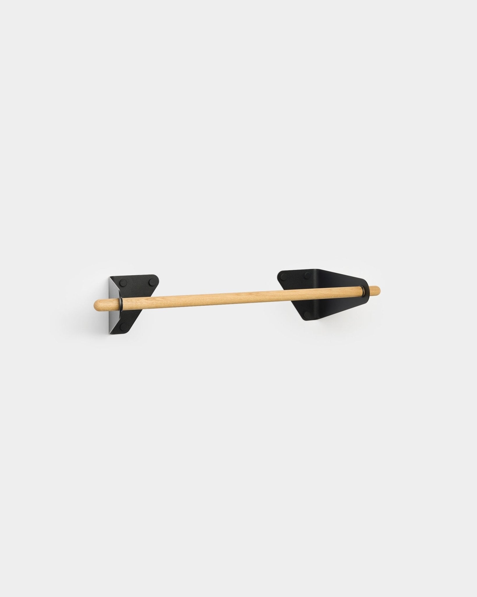 WoodUpp toilet paper holder with a minimalist wooden rod and black triangular brackets, designed to coordinate with the Linn Coat Rail for Akupanel accessories.
